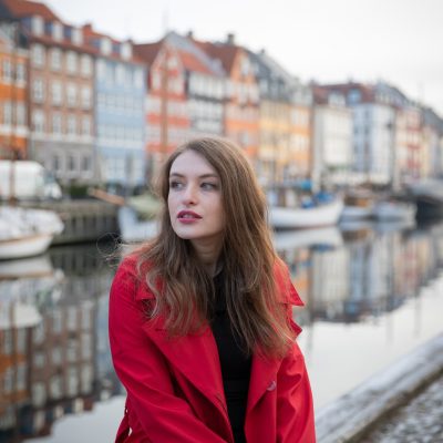 Attractive girl sitting, she is a tourist and is visiting Nyhavn in Copenhagen, Denmark.